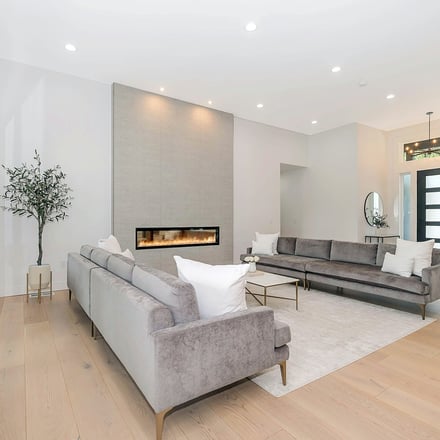 Modern living room with grey sofas, linear fireplace, and light wood floors
