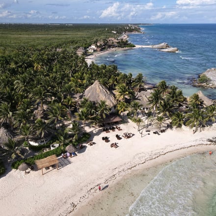 Aerial view of Tulum beach with palm palapas and turquoise Caribbean water