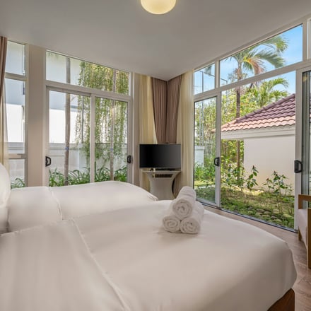 Bright bedroom with large windows overlooking a lush garden