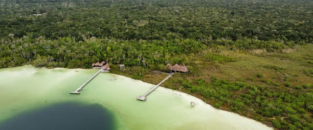 Aerial view of Laguna Kaan Luum with turquoise water, jungle canopy, and wooden piers near Tulum