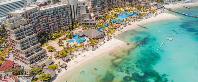 Vista aérea de la zona hotelera de Cancún con el Caribe turquesa, playa de arena blanca y piscinas de complejos turísticos