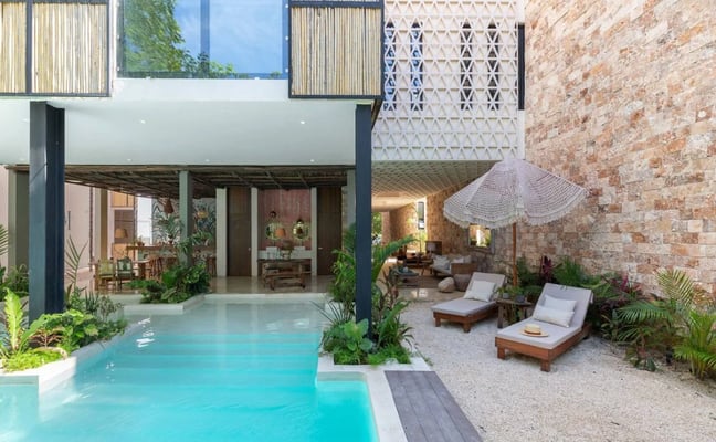 Terraza moderna con tina de inmersión, mesa de comedor, sillas tejidas, pérgola de madera y vistas a la piscina y al paisaje tropical